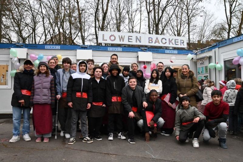 Gemeinschaftsfoto der Löwenklasse der Mönchbergschule Würzburg bei der Eröffnung der Schülerfirma Löwen Bäcker gemeinsam mit Klassleiterin Mareike Eder, Schulleiter Dr. Alban Schraut, Hausmeister Herr Wallrapp, 3. Bürgermeisterin Judith Roth-Jörg, Sozialreferentin Dr. Hülya Düber, Vorstandsmitglied der Sparkasse Mainfranken Jochen Schönleber und Landtagsabgeordneten Björn Jungbauer. 